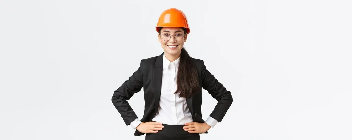 A professional, smiling Asian female construction engineer and architect wearing a black suit and a safety helmet, lo